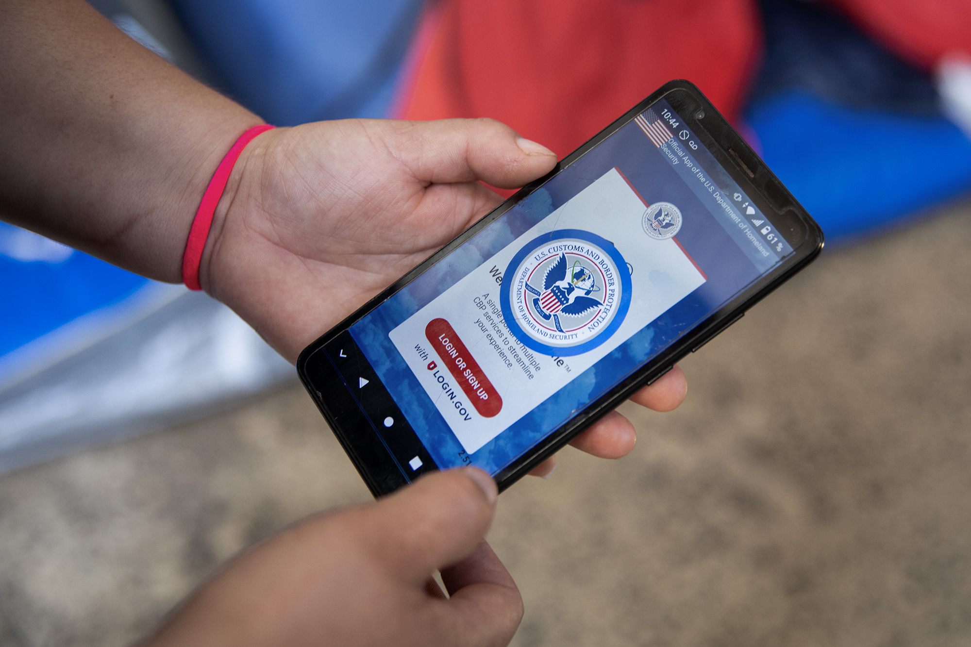 A person holds a cellphone with a message that displays a red, white and blue logo from the U.S. Department of Homeland Security.
