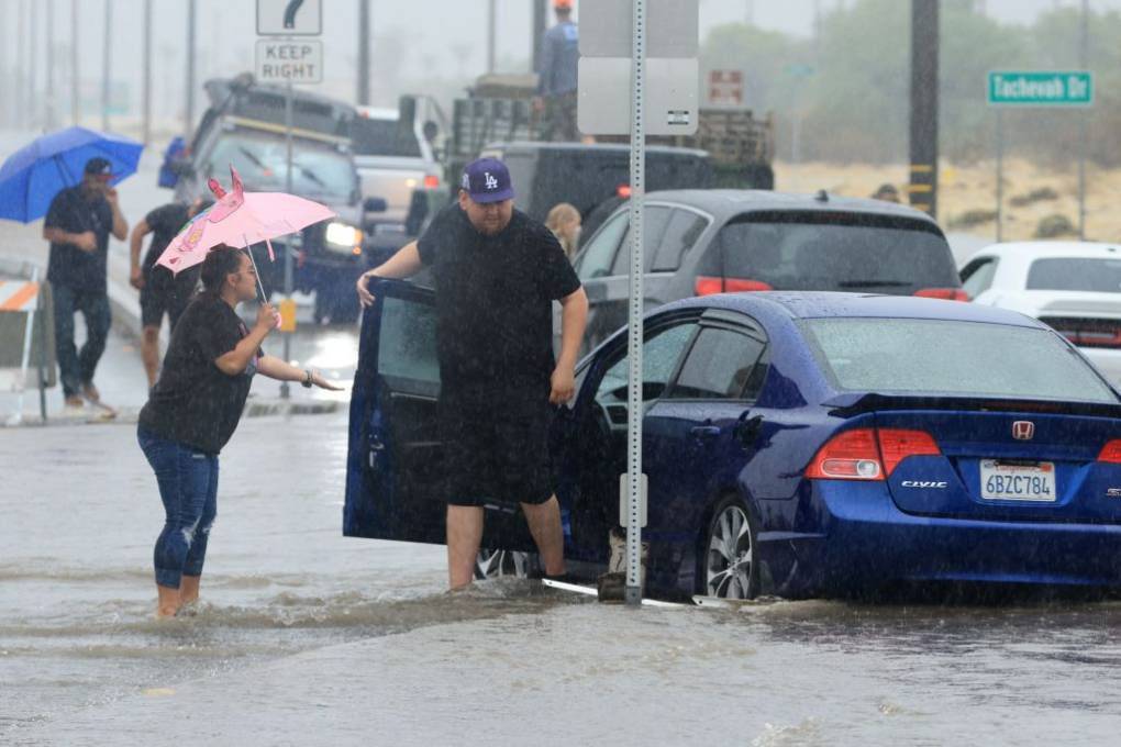 People struggling in stranded cars and traffic on a rainy road.