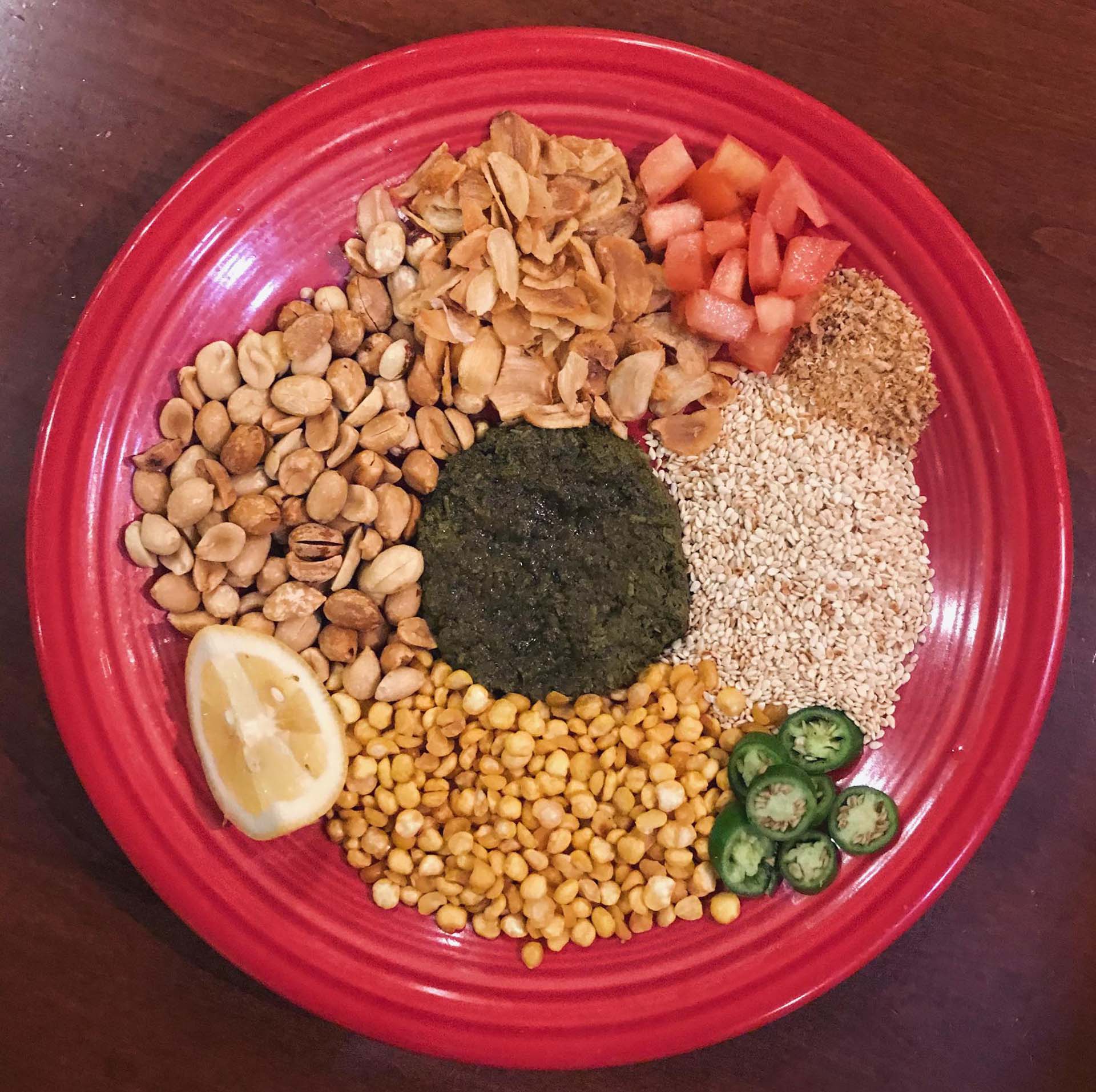 A Burmese tea leaf salad, premixing, with piles of various seeds and nuts arranged on the plate.