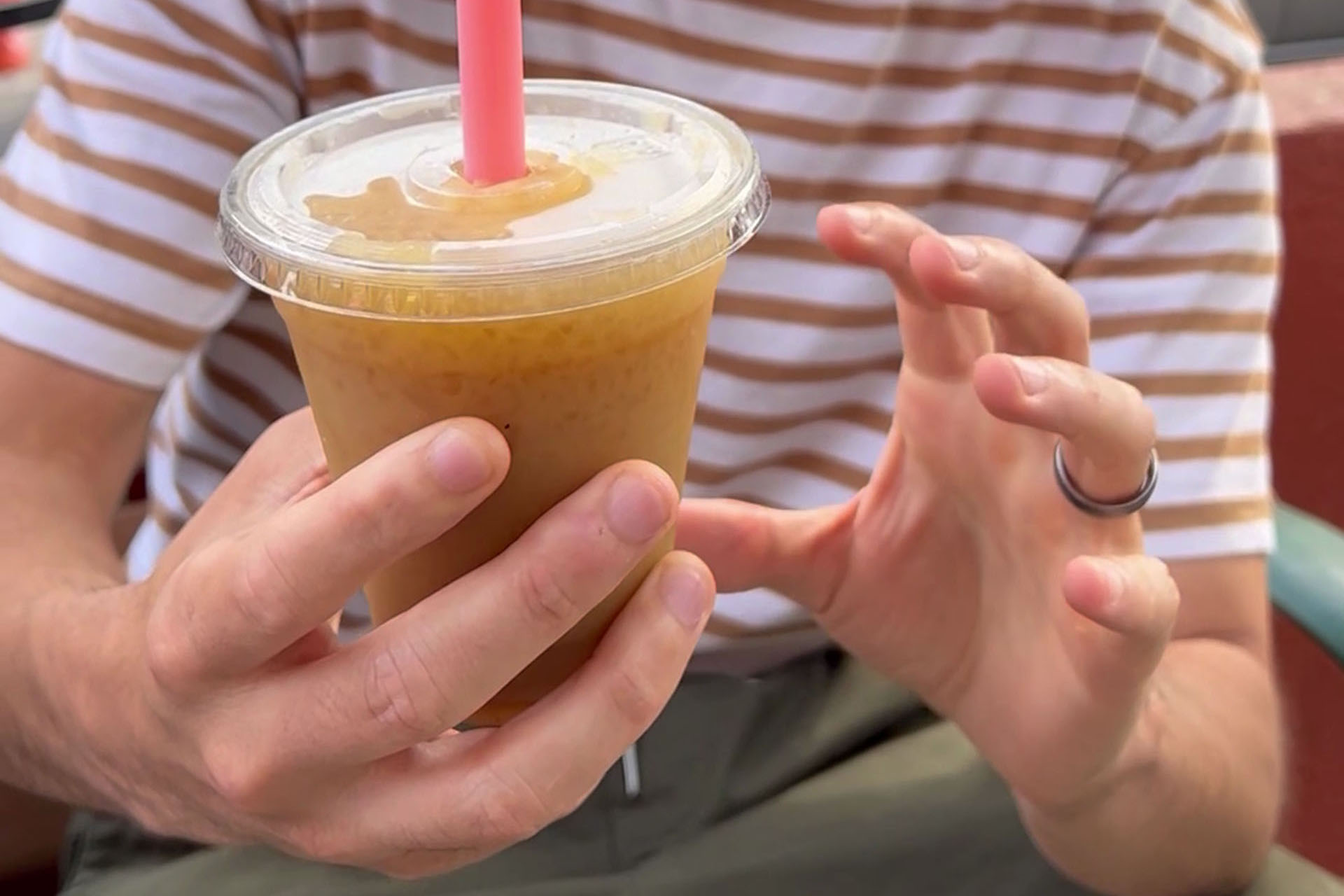 the author holds up a plastic cup of Tejuino, which is a Mexican beverage made with masa and lime ice cream