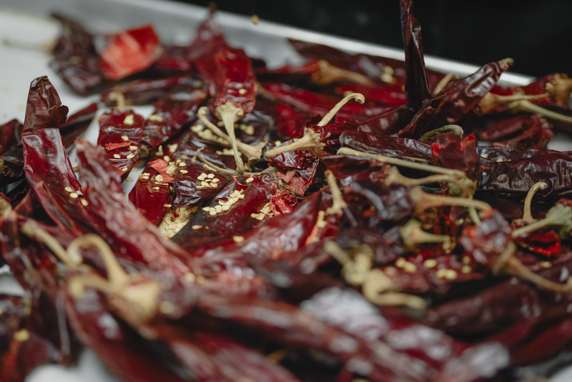 Chiles ranging in color from red to deep maroon, their seeds and stems are seen in close-up.