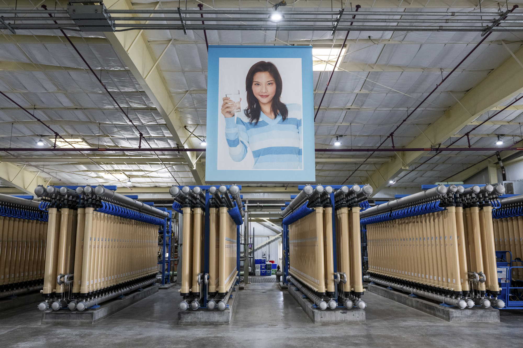 A large room full of industrial equipment and a poster of a person holding a glass of clear water.