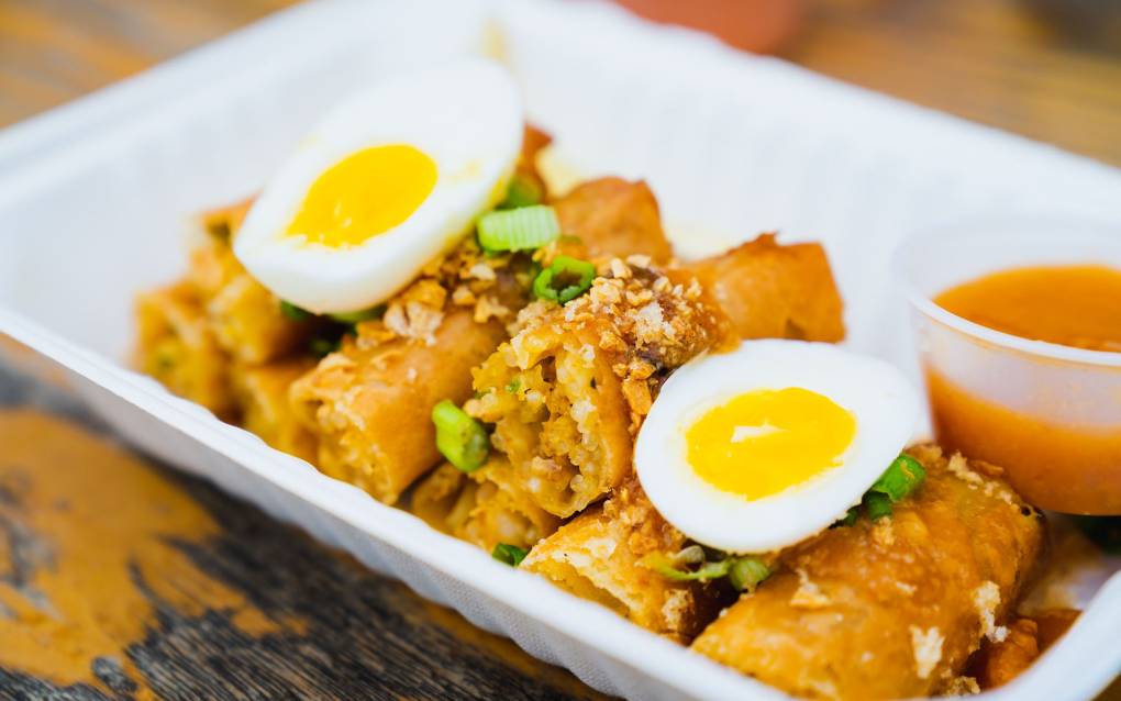 A plate of lumpia topped with slices of hard-boiled egg.