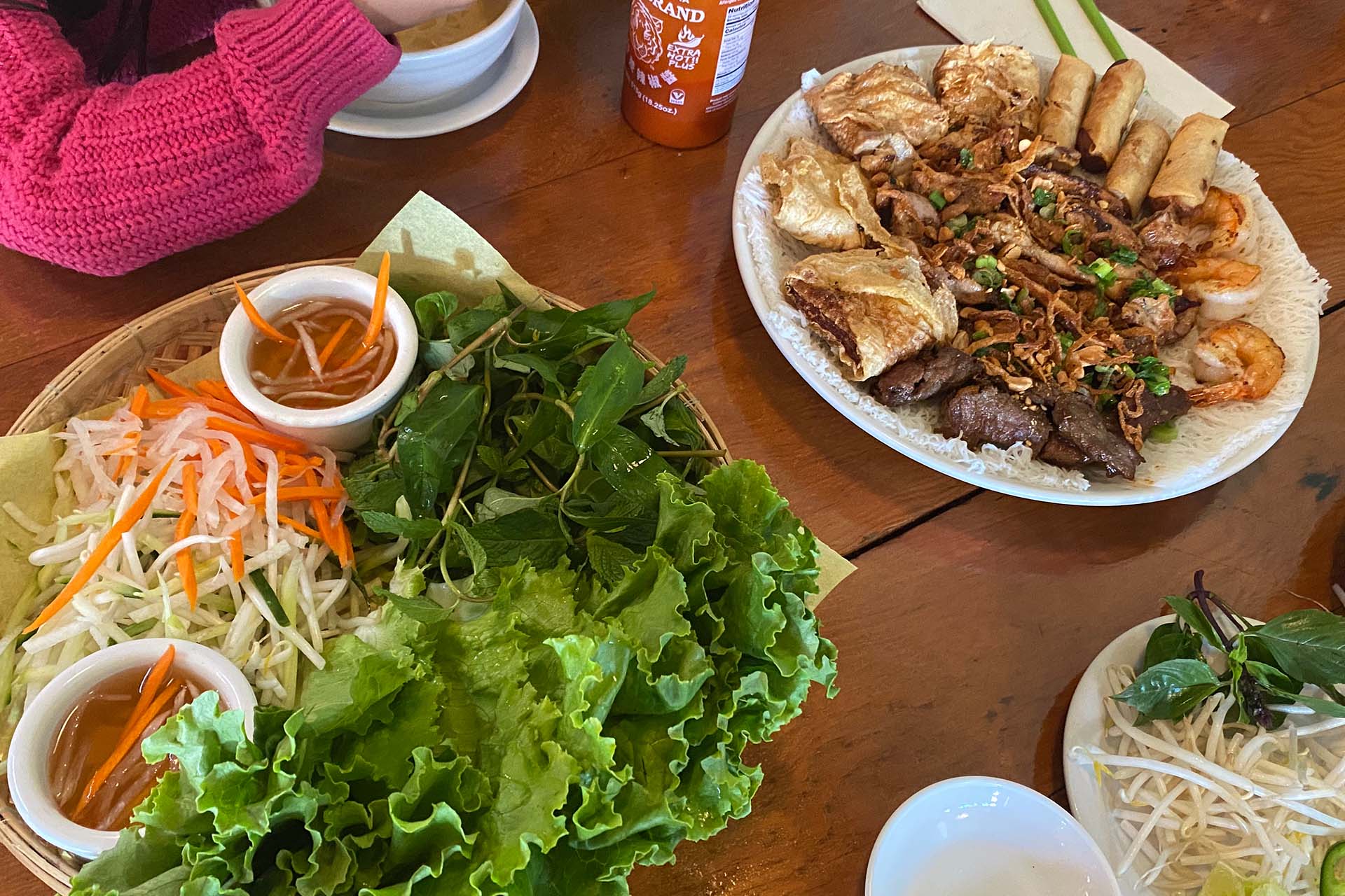 A spread of Vietnamese spring roll fillings next to a plate covered with lettuce and herbs.