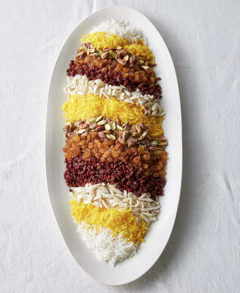 A white oval plate with symmetrical lines of rice, grains and beans arranged on it.